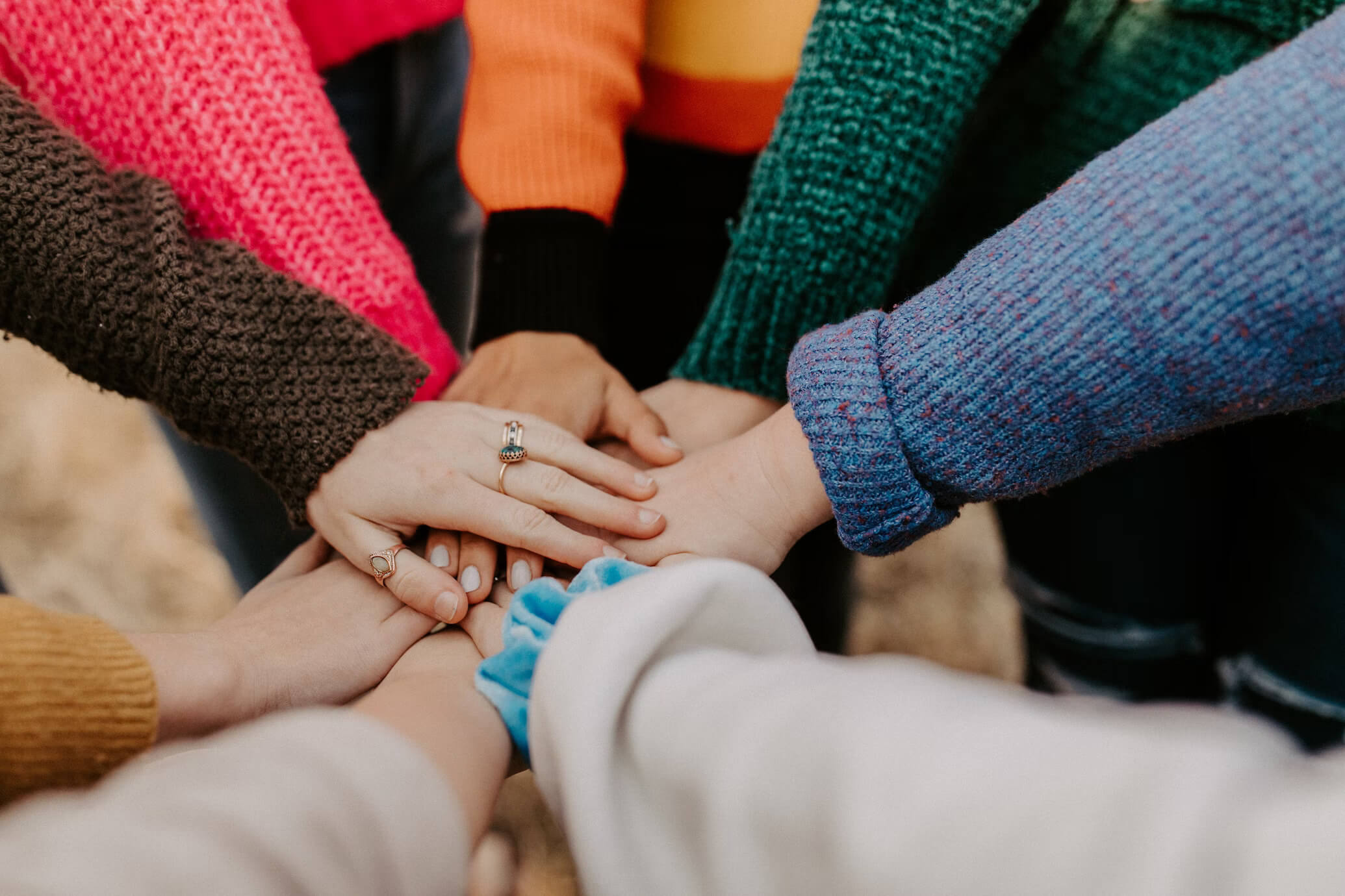 Various people's hands all placed together in a huddle.