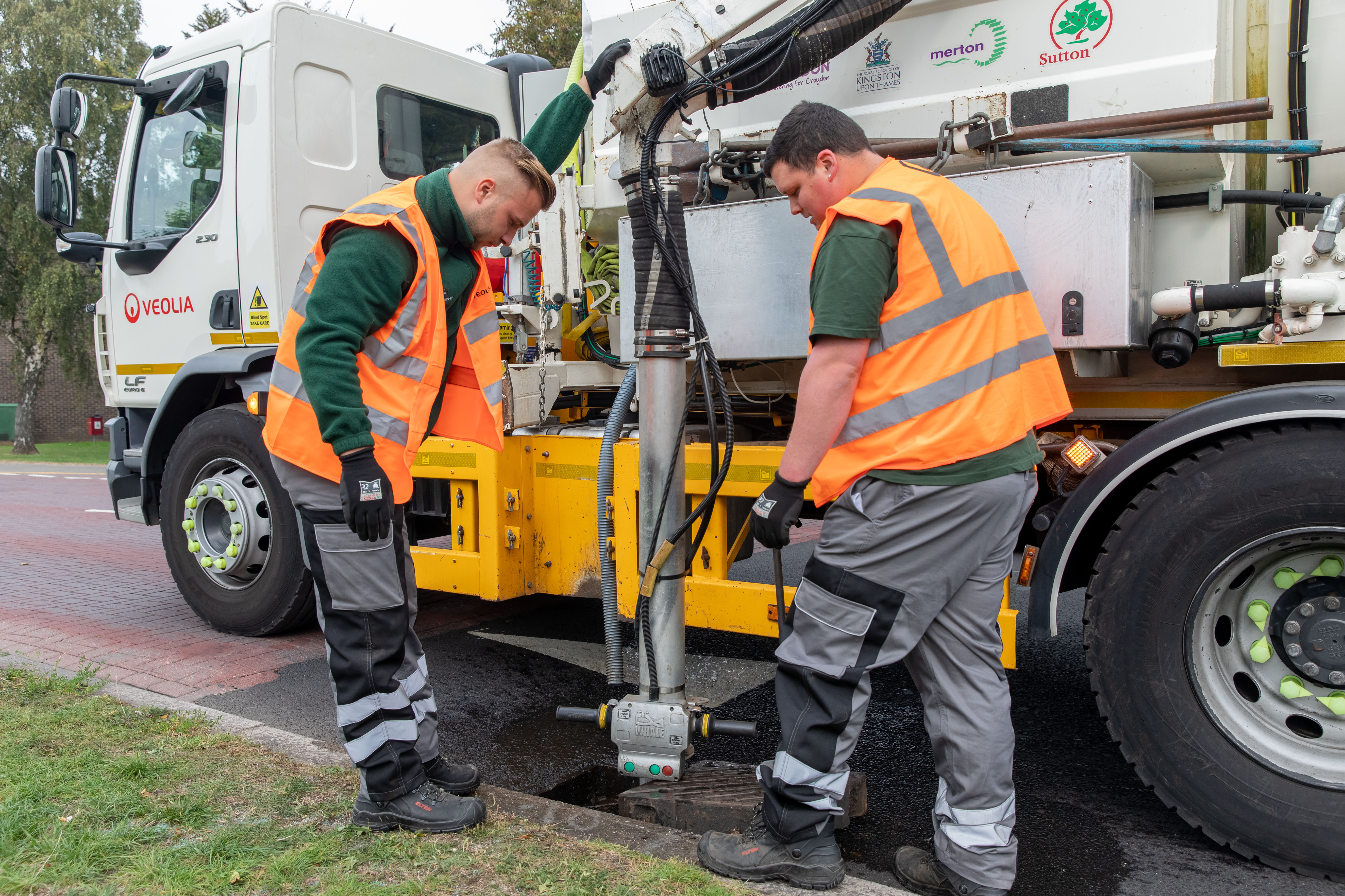 Two crew members cleaning a blocked gully with their tanker