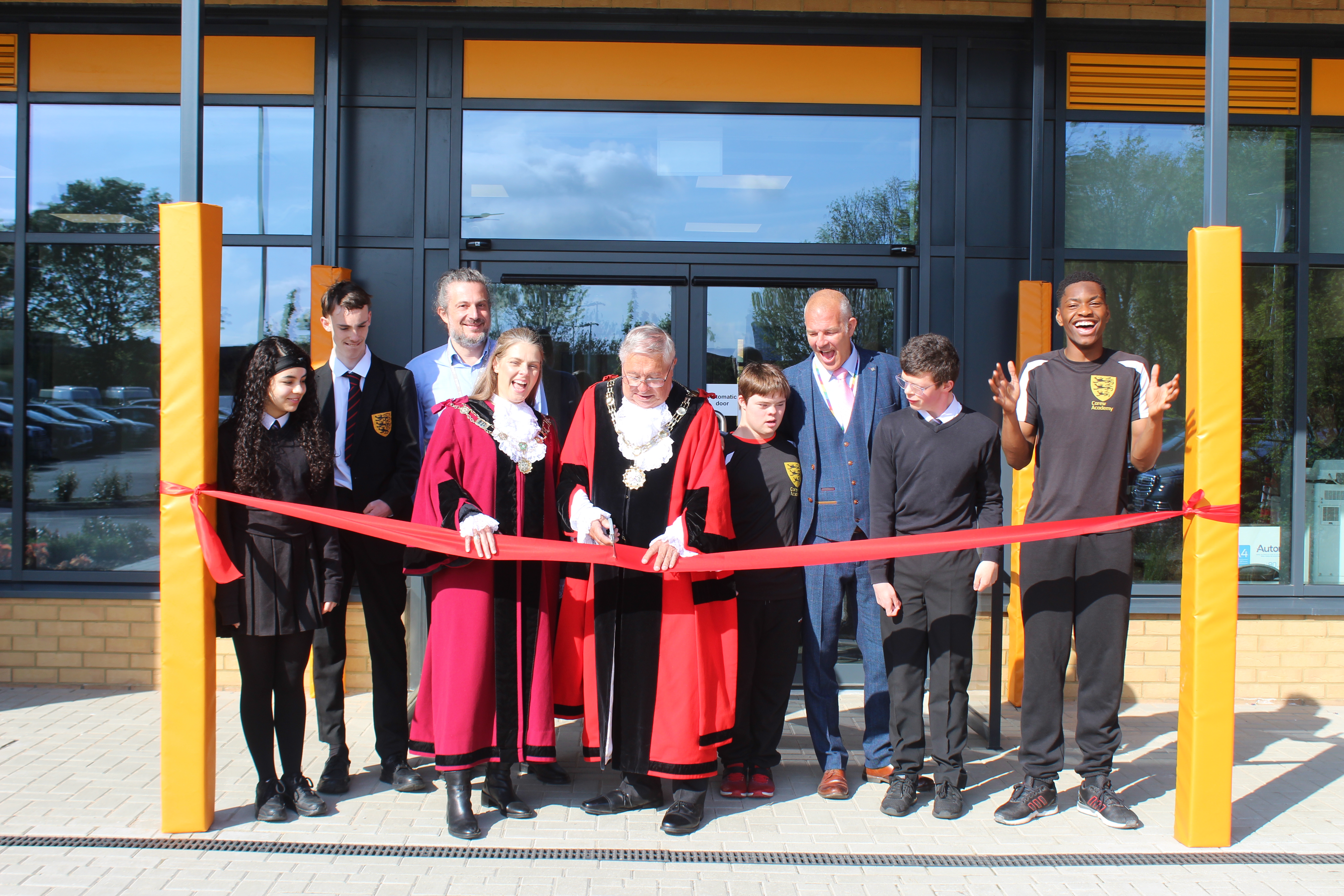 Picture of the Mayor of Sutton , Councillor Colin Stears , and the Deputy Mayor, Cllr Louise Phelan cutting the ribbon of the new purpose-built Carew Academy  alongside pupils and staff.